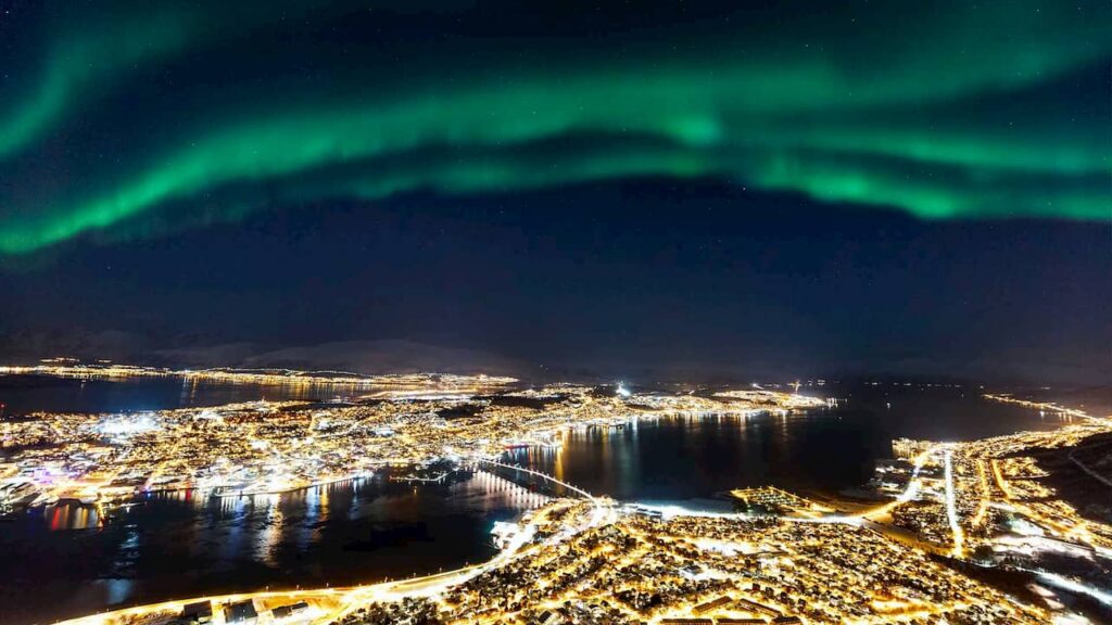 Tromso vista a noite da estação do teleférico Fjellheisen com a aurora boreal. - lugares imperdíveis.